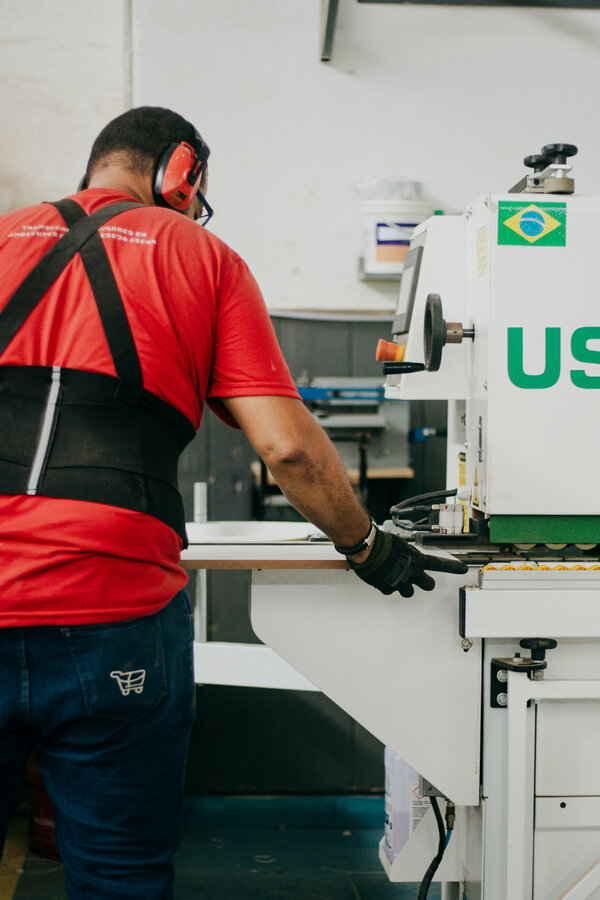 Operador de produção Haute, camisa vermelha, na bancada